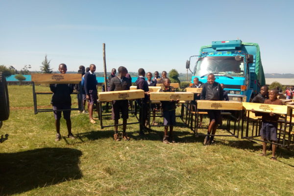 Dagoretti Primary School - Nakuru, pupils carrying delivered desks